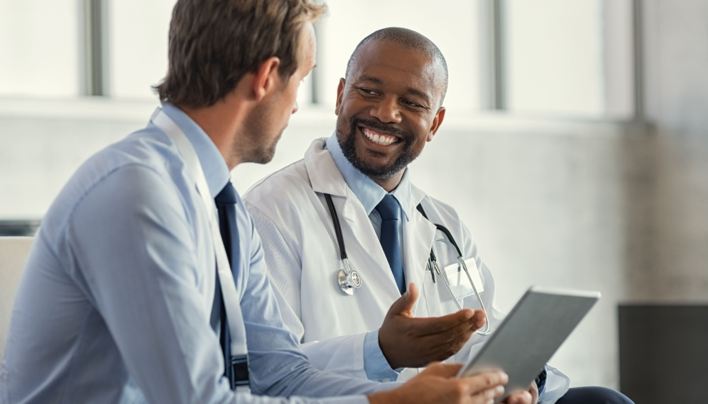 Smiling doctor speaking to man; stakeholder engagement concept