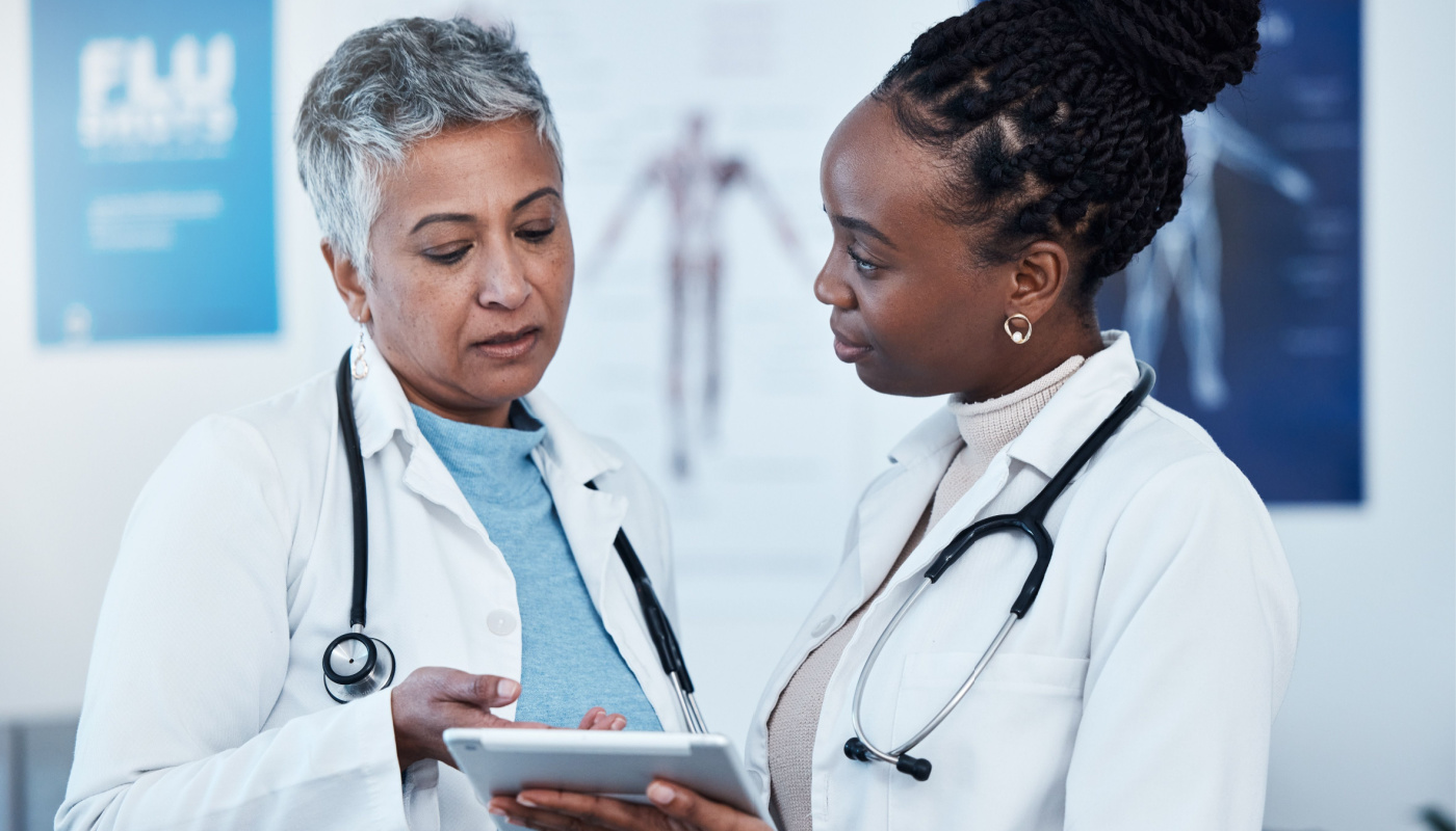 Two healthcare professionals in discussion, using tablet; stakeholder engagement concept