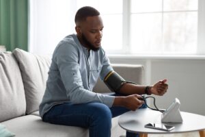 Man checking his own blood pressure at home; decentralized trials concept