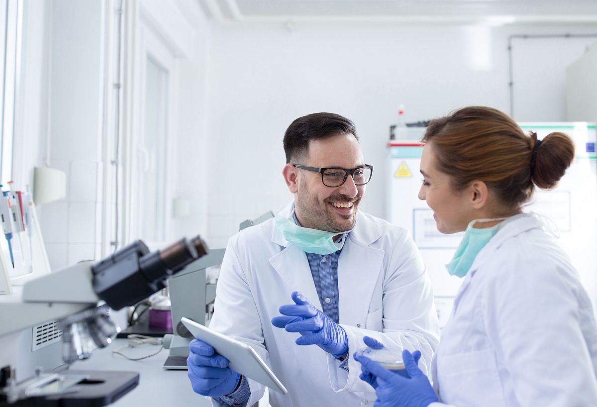 Two smiling healthcare professionals in lab; synthetic data concept