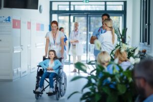 Healthcare worker pushing little girl in wheelchair in a hospital; rare disease clinical trials challenges concept