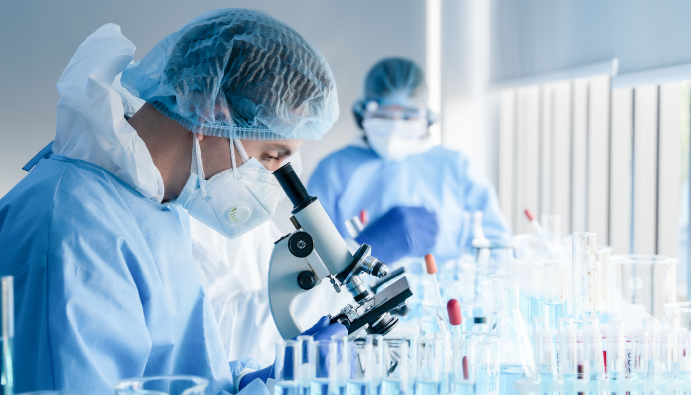 Lab technician looking through microscope; umbrella trials concept