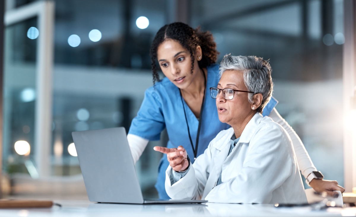 Healthcare professionals discussing findings, using laptop; generative AI concept