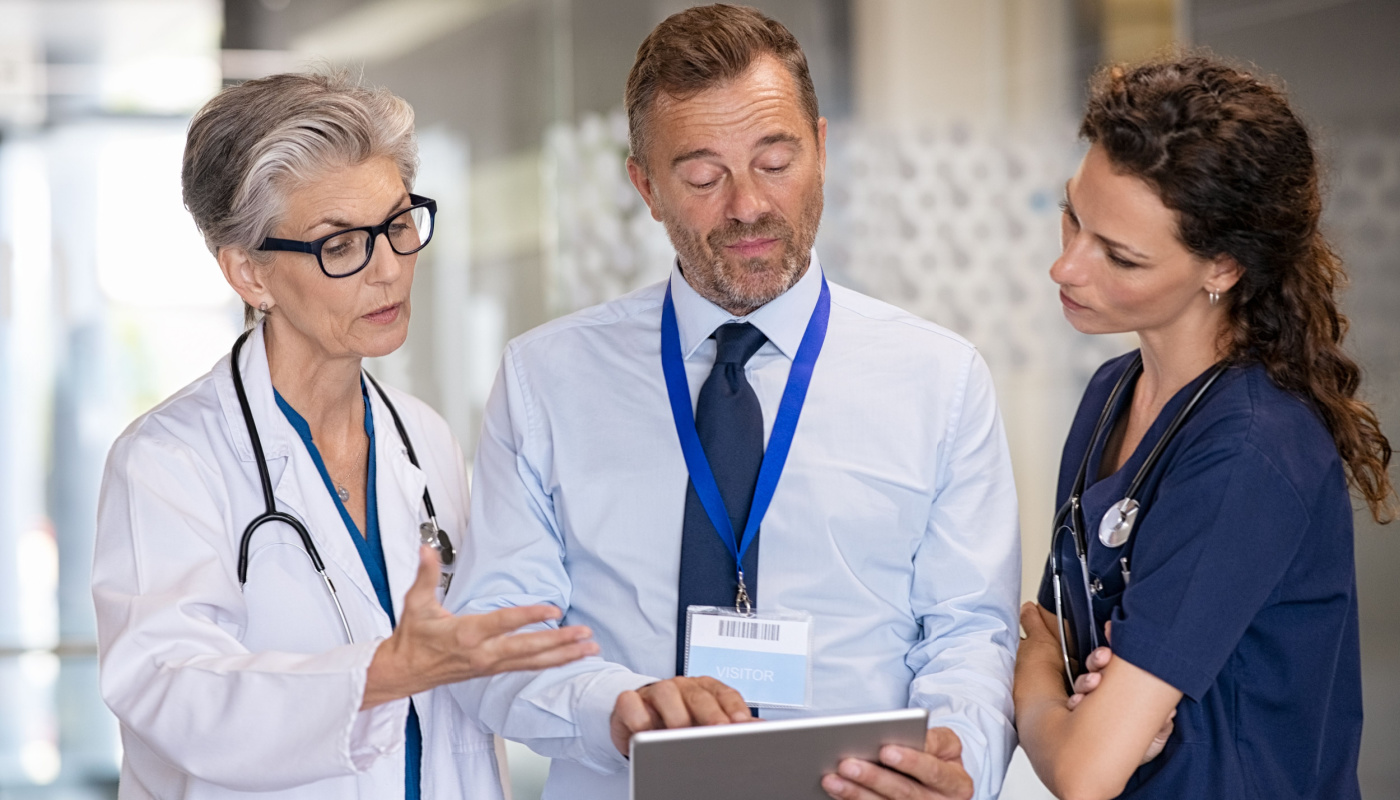 Three doctors in a hallway meeting; data compliance and harmonization concept