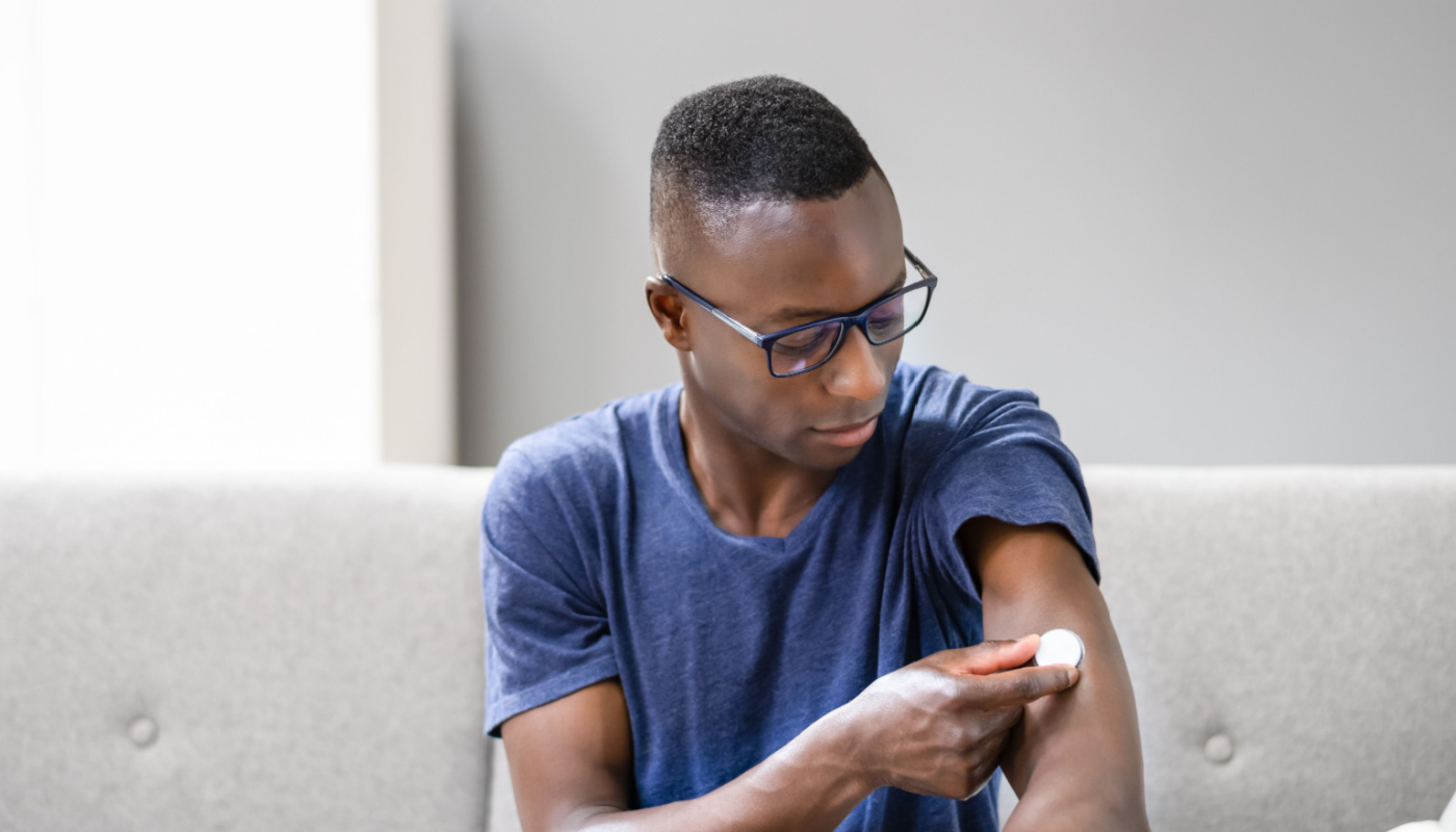 Man Testing Glucose Level With A Continuous Glucose Monitor On His Arm; data management challenges concept