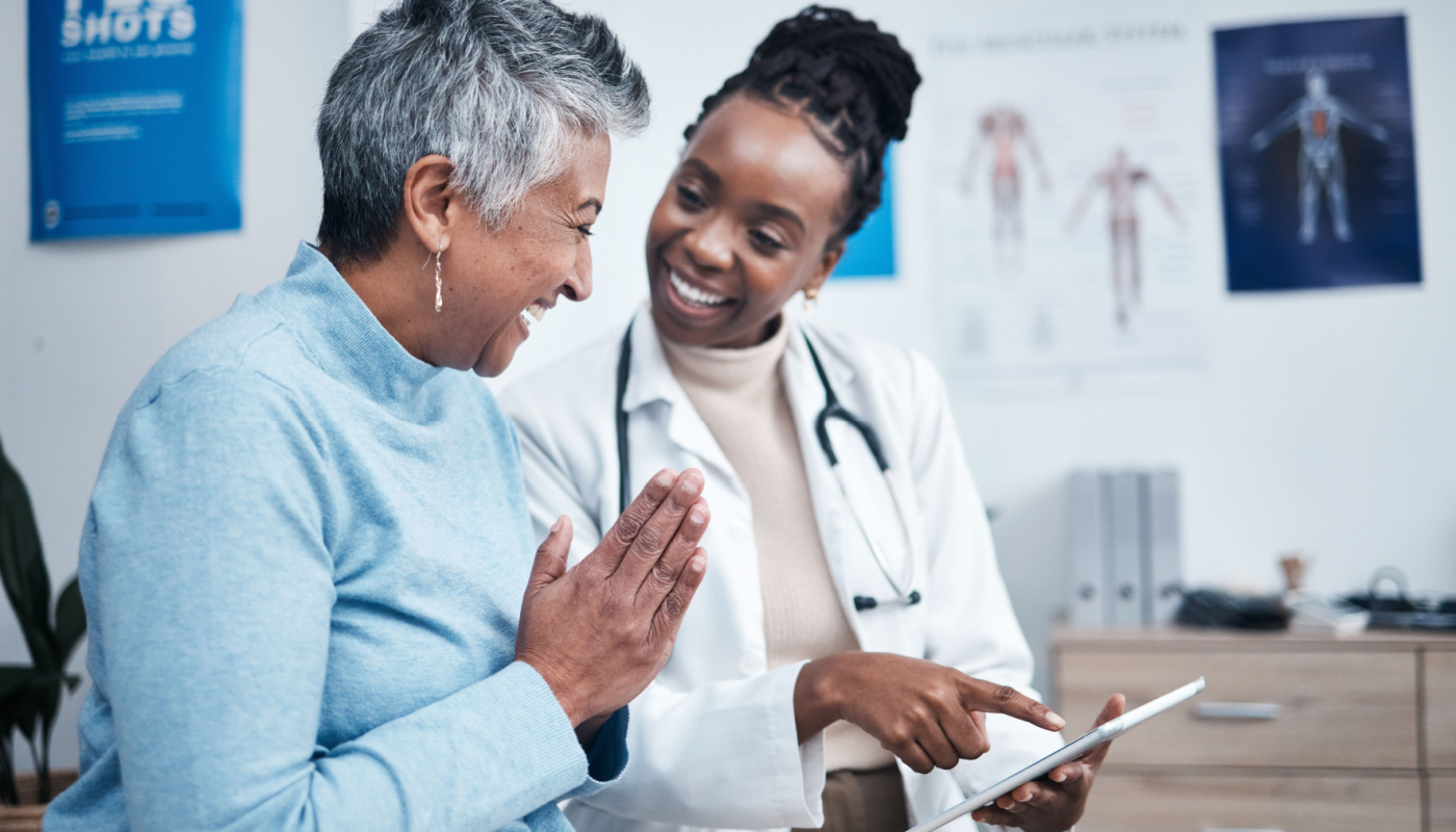 Doctor and patient looking at tablet and smiling; patient-centric care concept