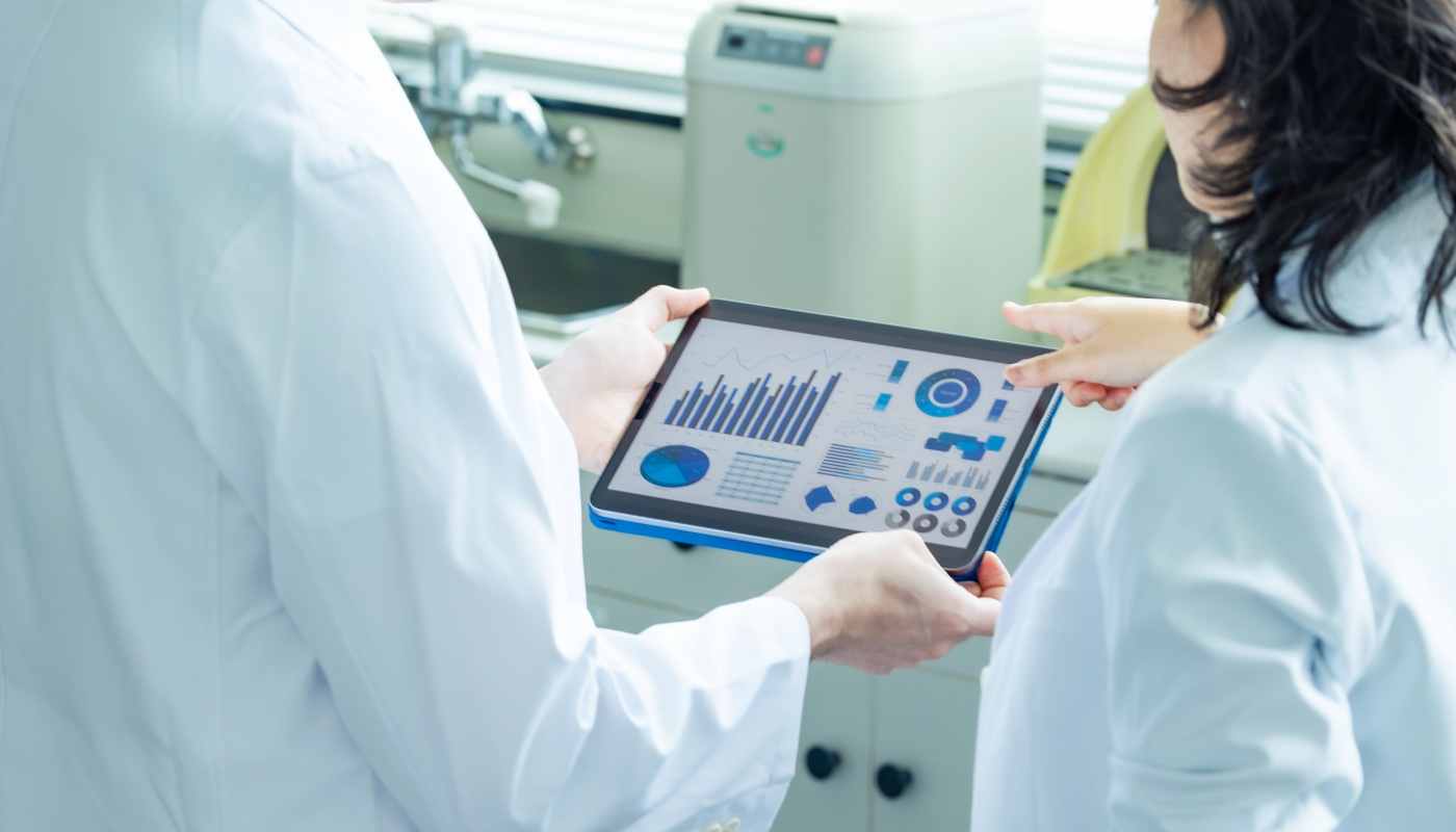 Researchers looking at tablet data in the lab; clinical trial costs concept