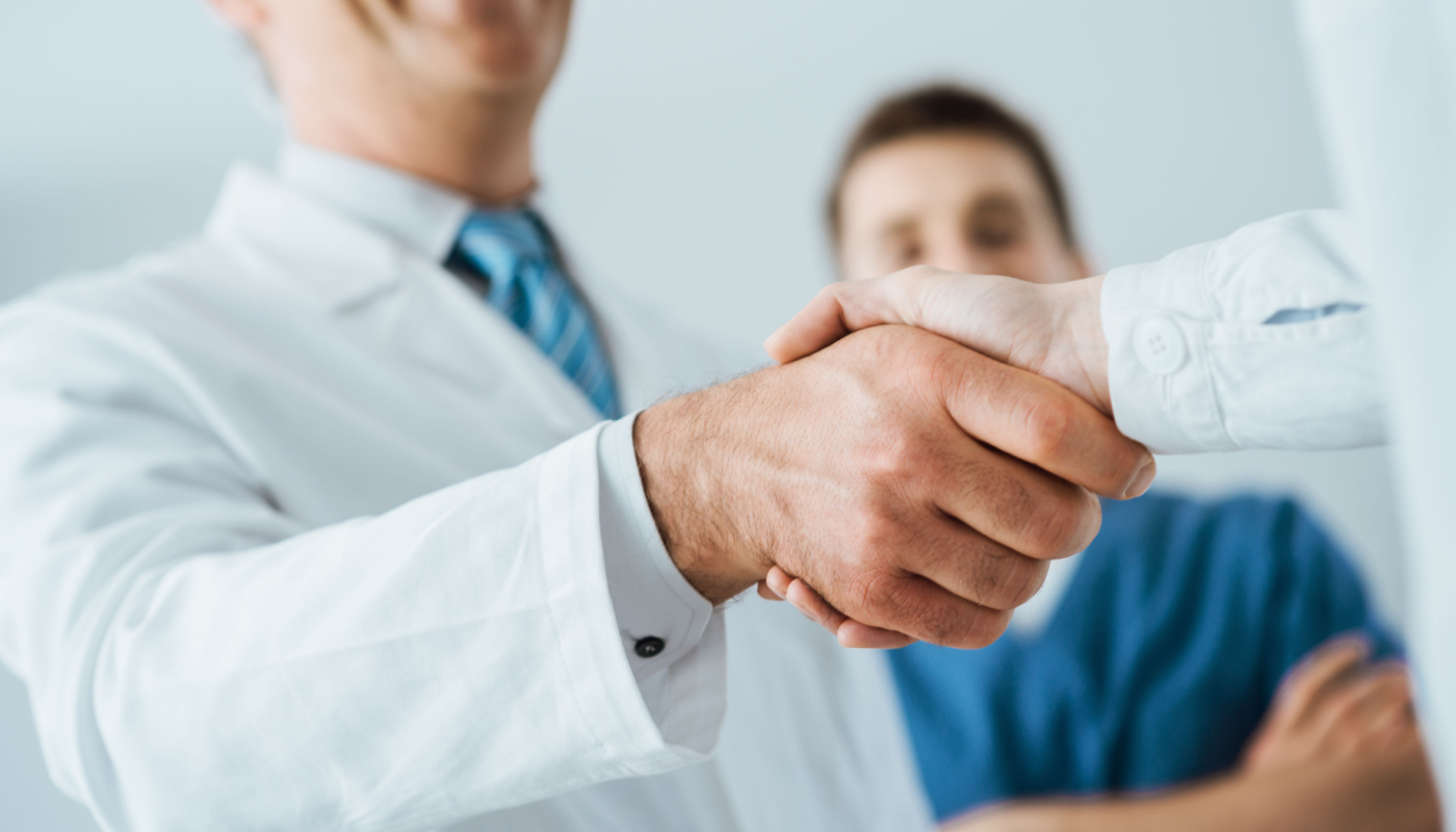 Business and healthcare professionals shake hands at hospital; meeting KOLs concept