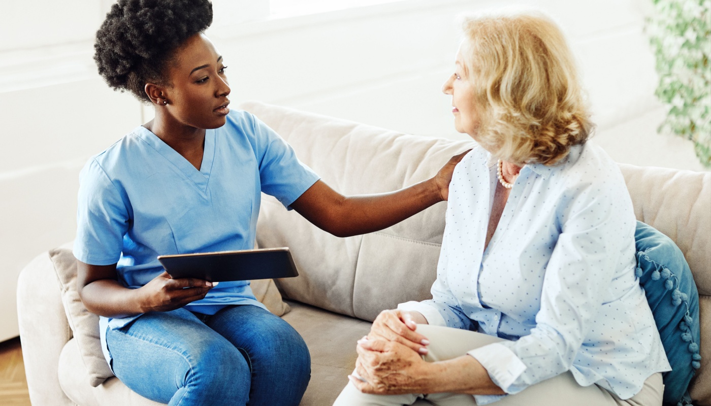 Caregiver holding a tablet and talking to a patient; streamlining clinical trials concept