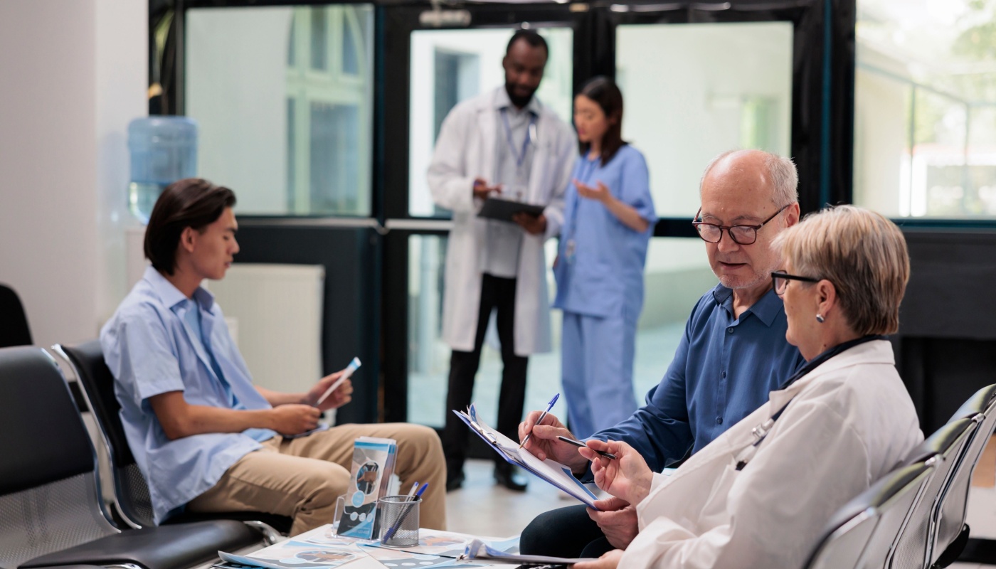 Senior specialist sitting in hospital lobby explaining diagnosis to elderly patient; provider engagement concept