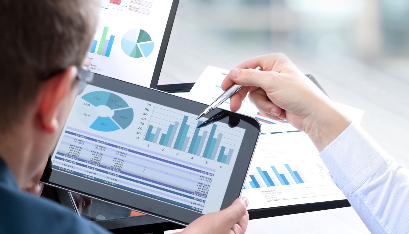 Colleagues analyzing financial figures on a digital tablet; competitive intelligence concept