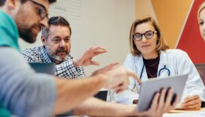 Healthcare workers with tablet meeting in hospital boardroom; KOL relationships concept